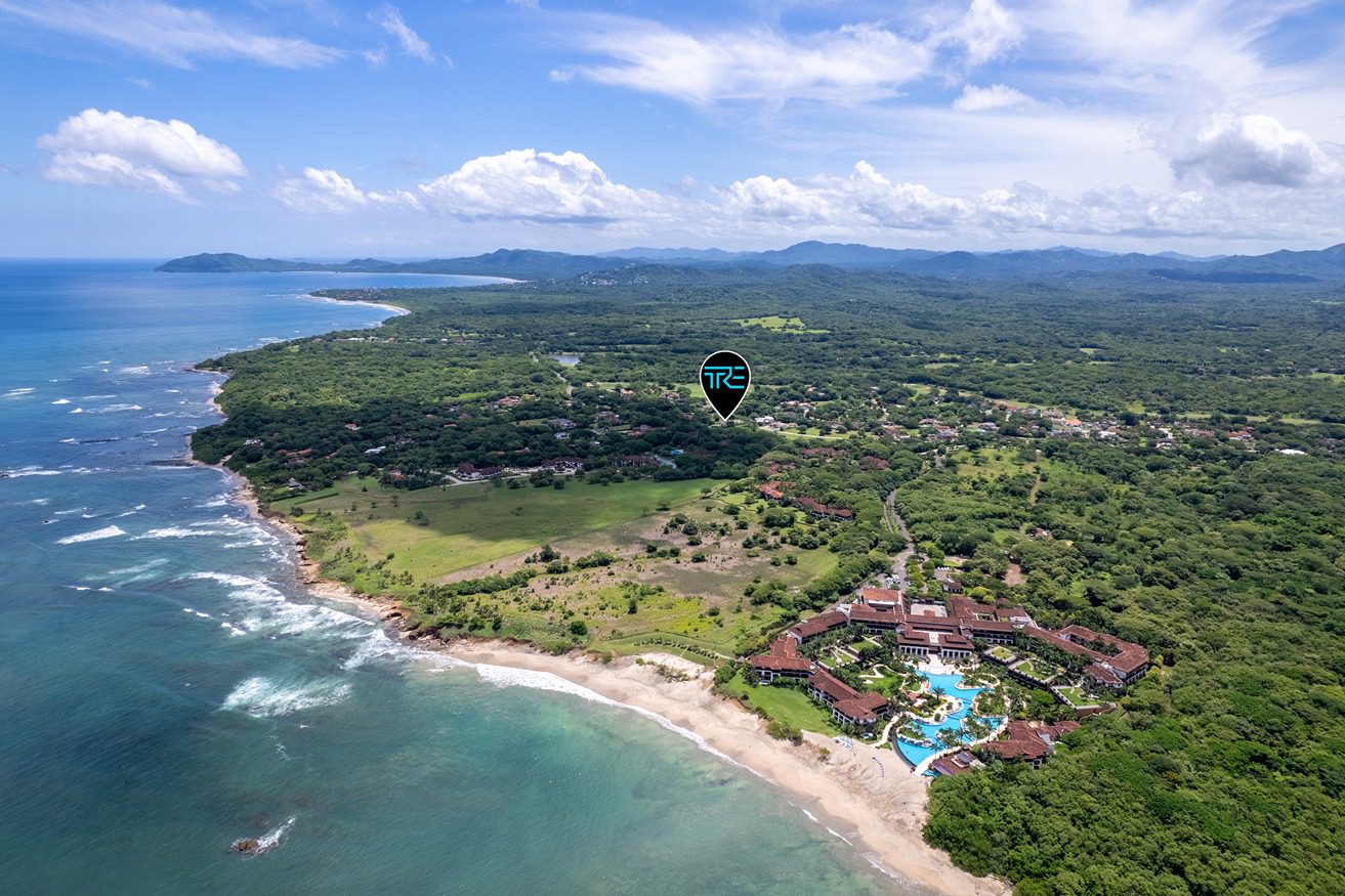 The Hacienda Pinilla coastline from the air, with surf along a wooded shore
